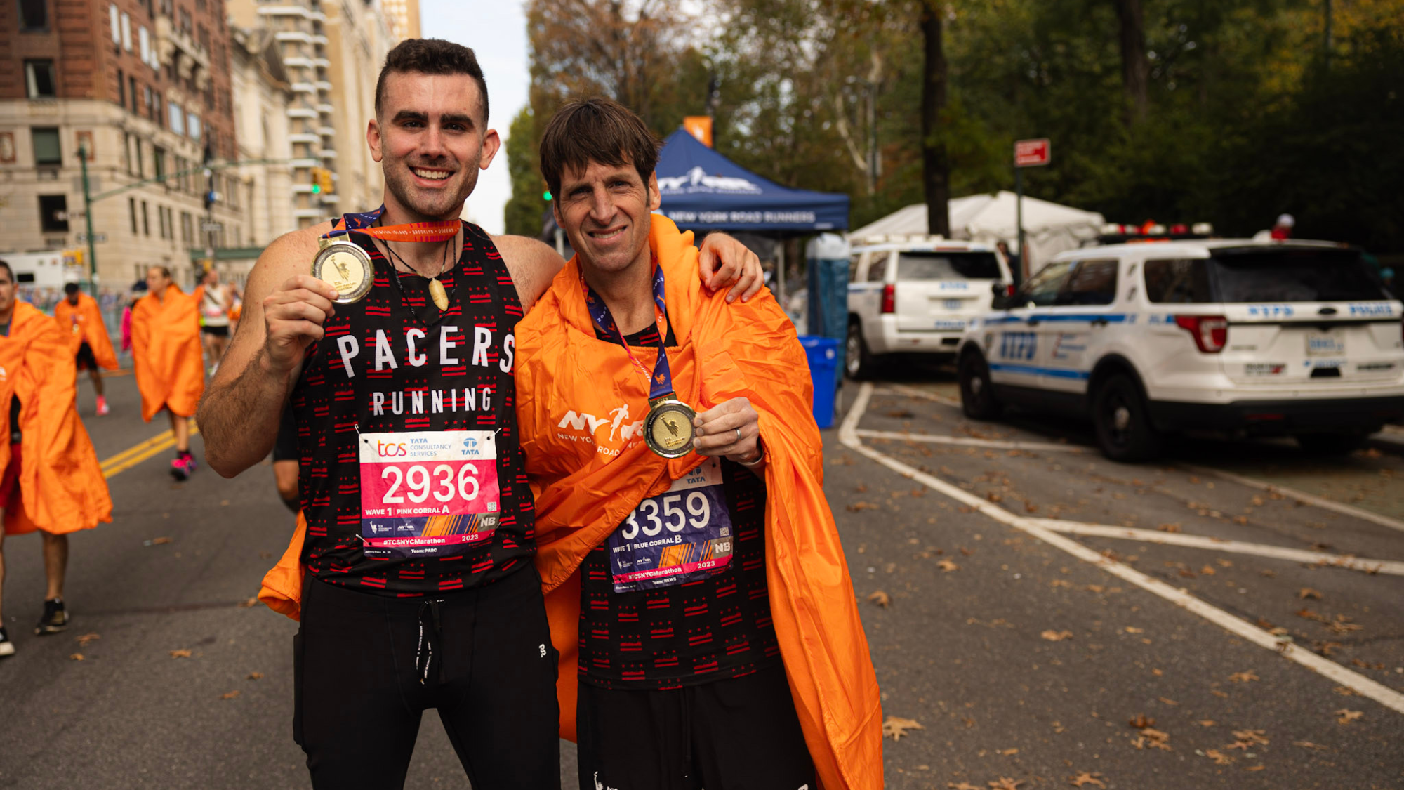 Two men with arms around each other after finishing the New York Marathon. One man is Chris Farley, the owner of Pacers Running. He is holding his medal and smiling.